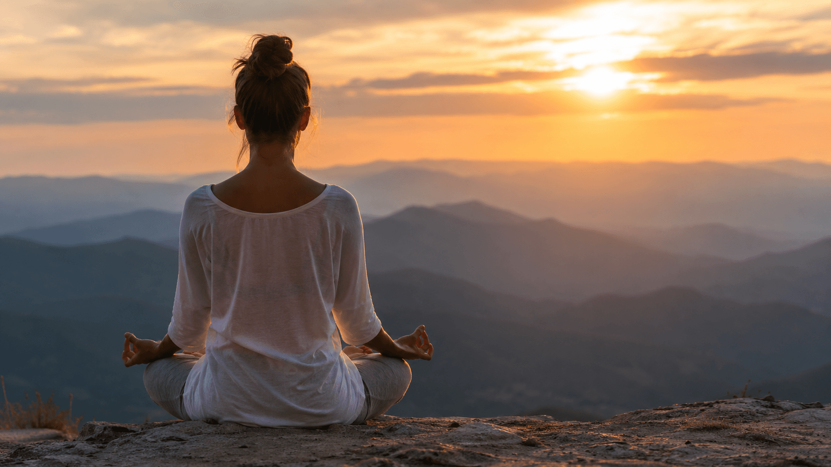 Person meditating outdoors at sunrise